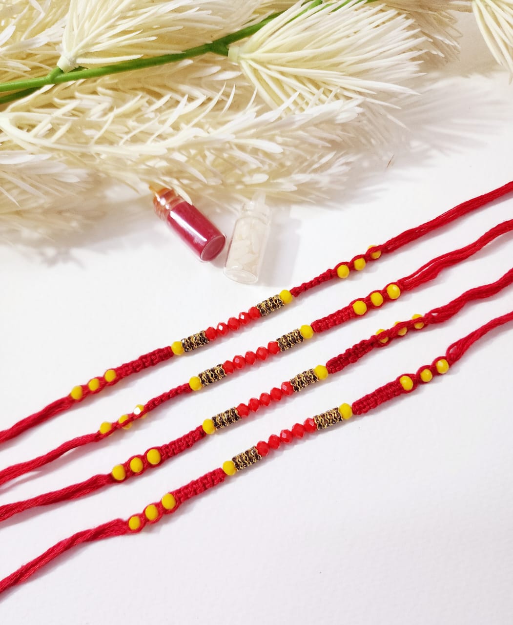 Three red beaded bracelets with gold accents on a white background