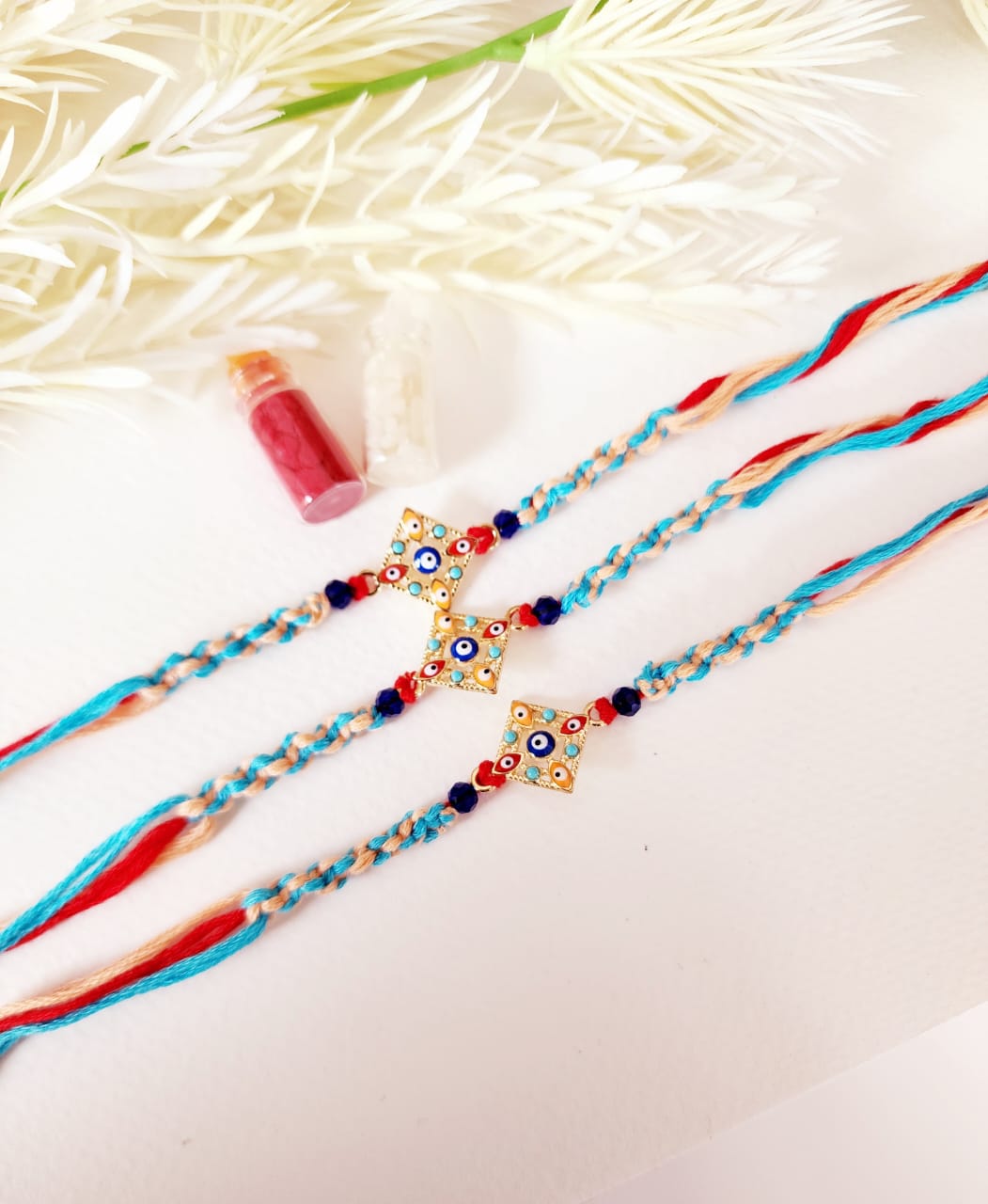 Two colorful rakhi necklaces with decorative beads on a light background