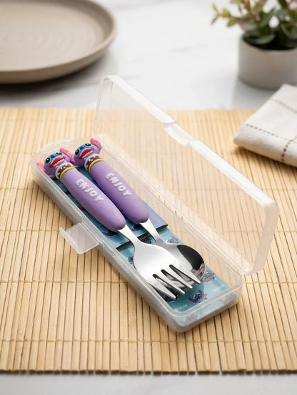 A children's stainless steel cutlery set with purple handles and colorful decorative ends, stored in a clear plastic case on a bamboo mat.