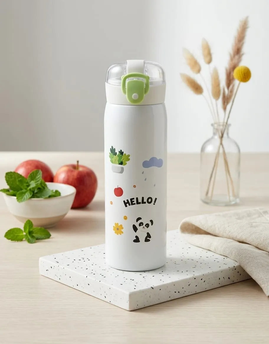 White water bottle with cartoon designs on a table with apples and a vase in the background