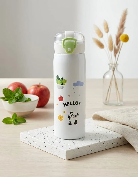 White water bottle with cartoon designs on a table with apples and a vase in the background