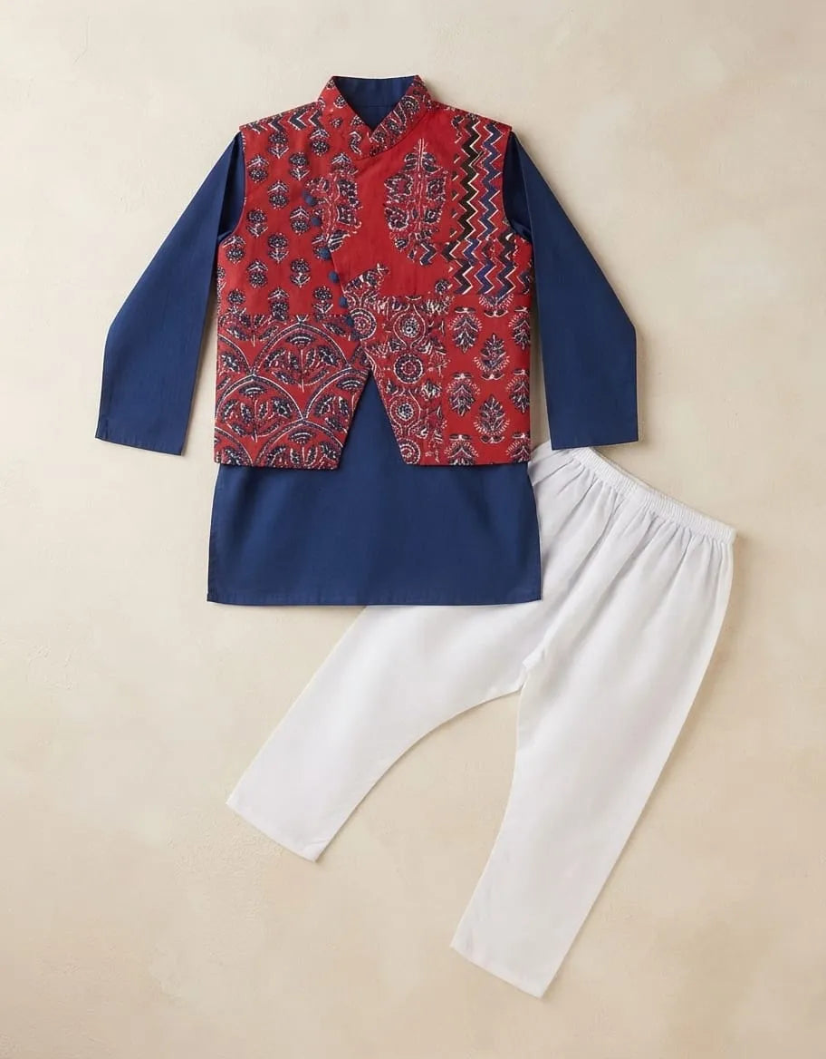 A children's traditional outfit laid flat on a beige background, featuring a navy blue kurta with a red patterned vest and white pants.