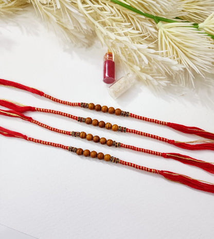 Three red strings with brown beads on a white surface with dried plants.