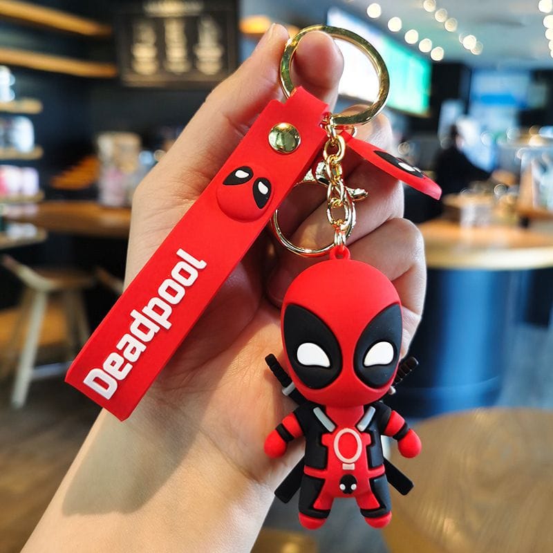 Deadpool keychain held in a hand with a blurred cafe background