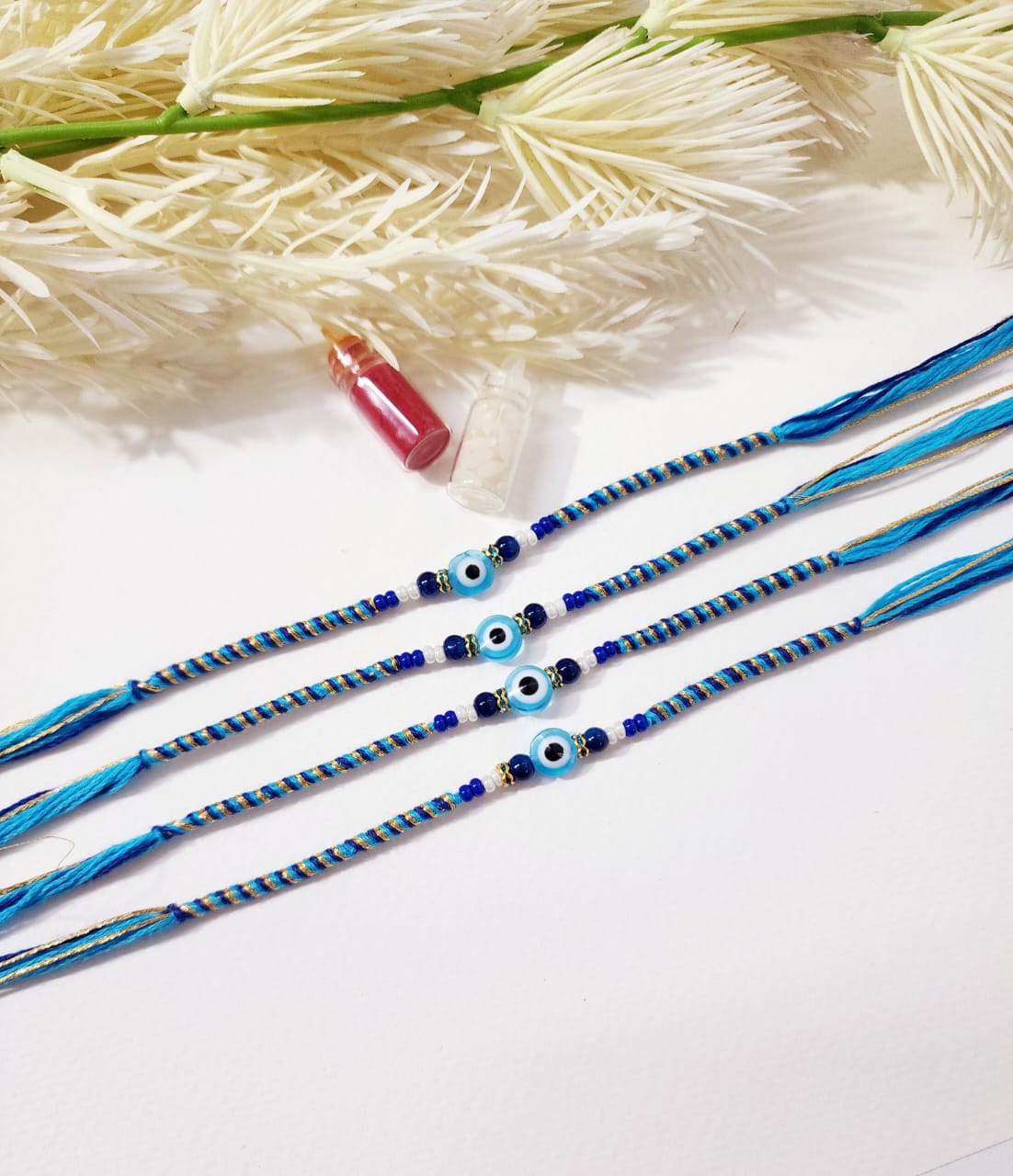 Blue and white beaded bracelets with small bottles on a white background