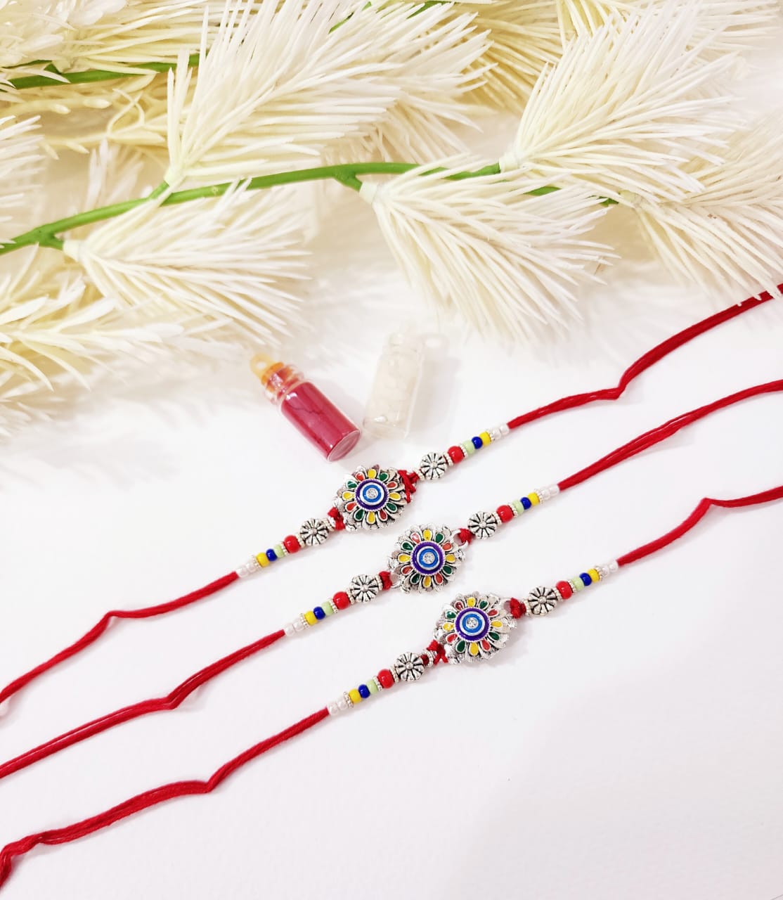 Two red rakhi ribbons with decorative beads on a white background