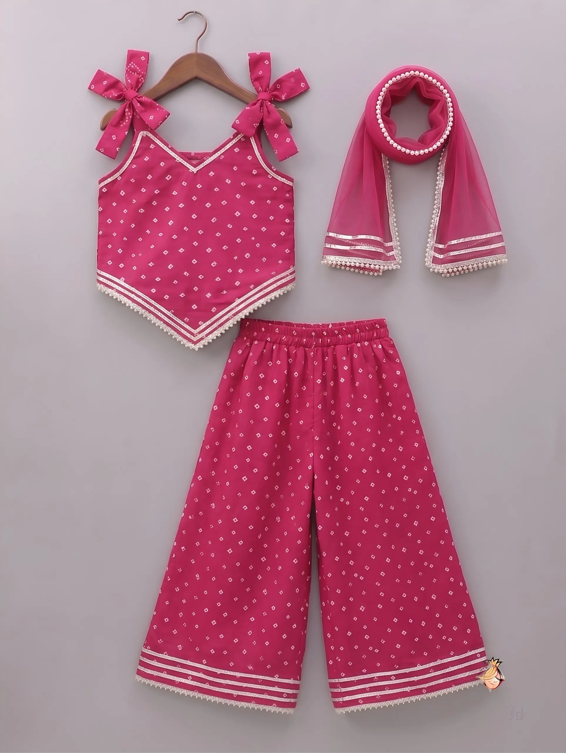A three-piece toddler girl's clothing set in vibrant pink, featuring a sleeveless top with bow details, matching wide-leg pants, and a scarf, all decorated with small white polka dots and white striped trim, displayed on a neutral gray background.