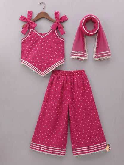 A three-piece toddler girl's clothing set in vibrant pink, featuring a sleeveless top with bow details, matching wide-leg pants, and a scarf, all decorated with small white polka dots and white striped trim, displayed on a neutral gray background.