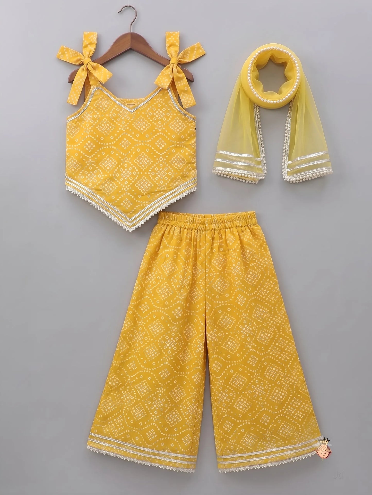 A three-piece toddler girl's outfit set in bright yellow, featuring a sleeveless top with bow shoulder straps, wide-leg pants, and a matching sheer scarf, all with a white geometric pattern, displayed on a gray background.