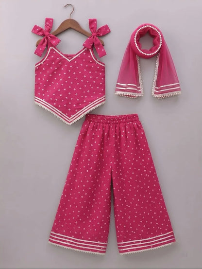 A three-piece toddler girl's clothing set in vibrant pink, featuring a sleeveless top with bow details, matching wide-leg pants, and a scarf, all decorated with small white polka dots and white striped trim, displayed on a neutral gray background.