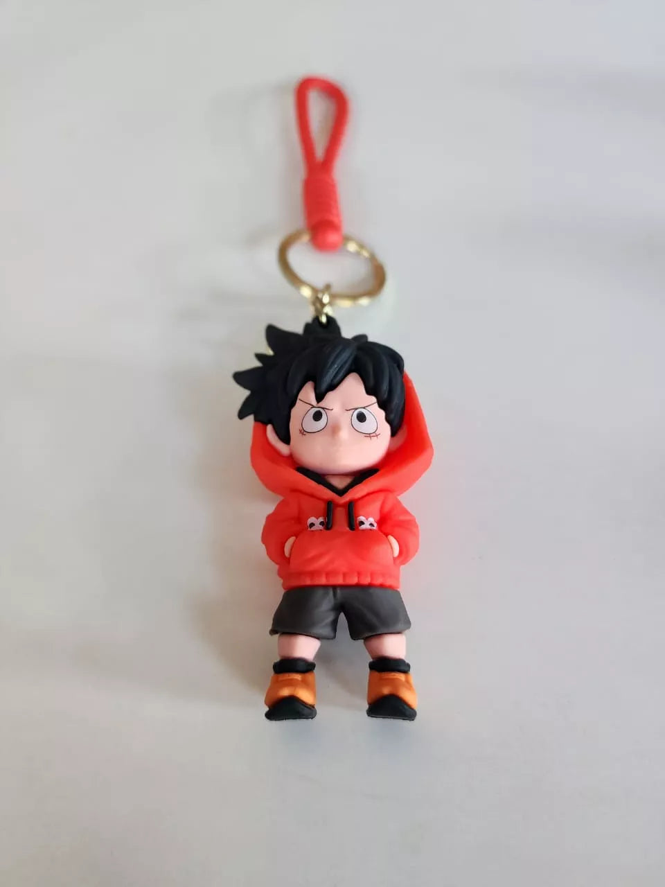Keychain of an animated character in a red outfit with black hair on a light gray background