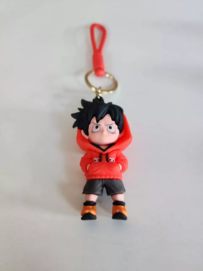 Keychain of an animated character in a red outfit with black hair on a light gray background