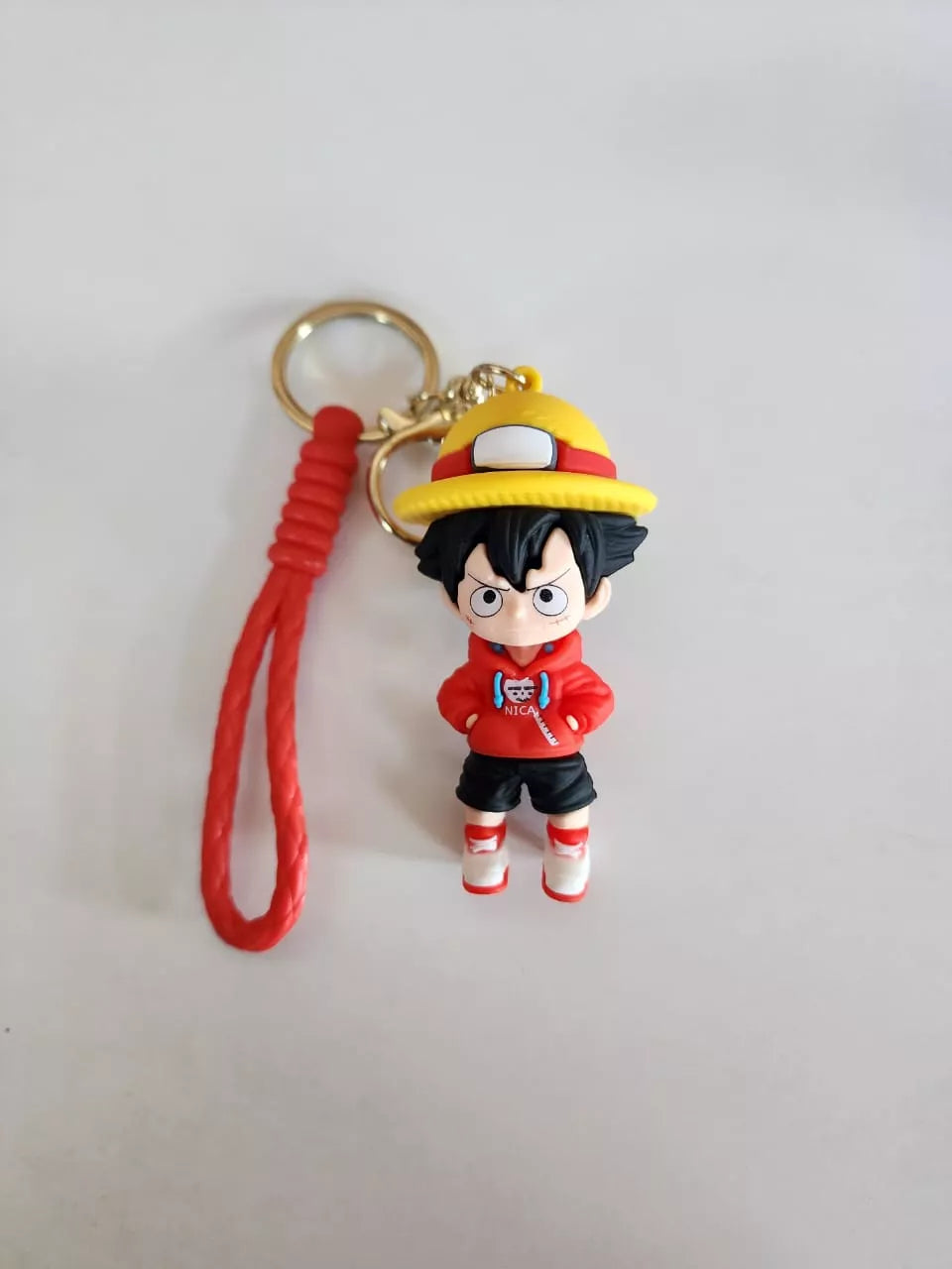 Keychain with a character in a red outfit and yellow hat on a light gray background