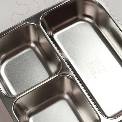 Close-up of a stainless steel compartment tray with three rectangular sections, showing the metallic interior surfaces and embossed recycling symbols.