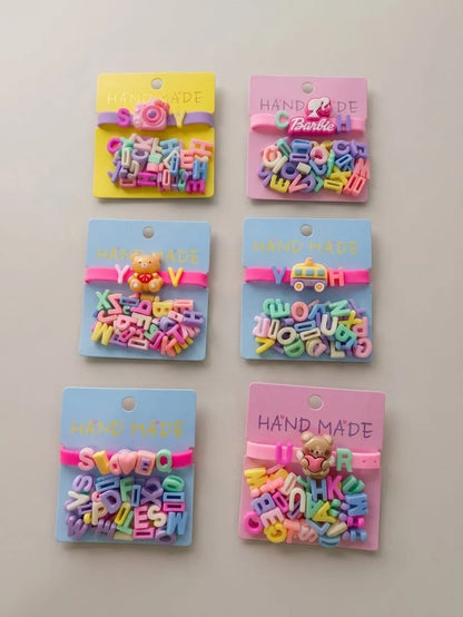 Six colorful handmade letter bead hair clips in various shapes and colors, each attached to a pastel-colored backing card with 'HAND MADE' printed on it, arranged in two columns of three on a light gray background.