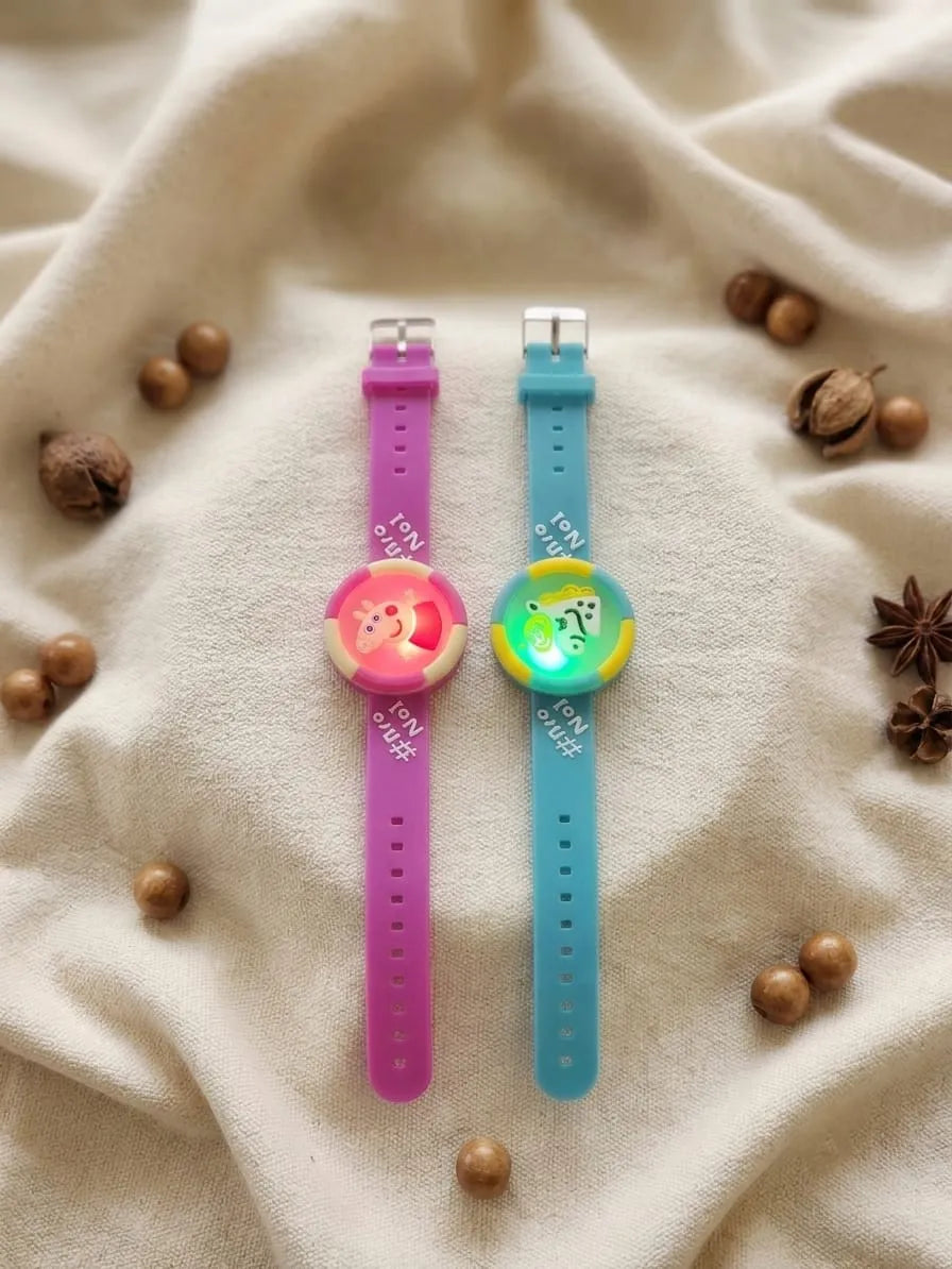 Two silicone watch bands with colorful round watch faces, displayed on a beige fabric background with scattered decorative nuts and star anise. One band is pink and the other is blue.