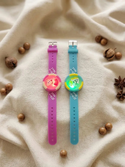 Two silicone watch bands with colorful round watch faces, displayed on a beige fabric background with scattered decorative nuts and star anise. One band is pink and the other is blue.