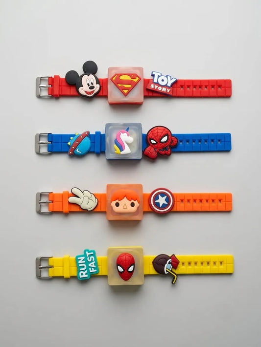 Four colorful silicone watch straps laid out horizontally on a light gray background, each with a character or logo charm in the center and a metal buckle on the left. The straps are red, blue, orange, and yellow, featuring Mickey Mouse, Superman, Toy Story, a space-themed charm, Spider-Man, a peace sign, a cartoon face, Captain America, a 'Run Fast' charm, and Spider-Man again.