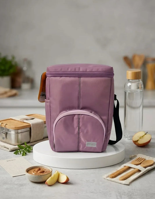 Purple insulated lunch bag on a kitchen counter with food items and a water bottle.