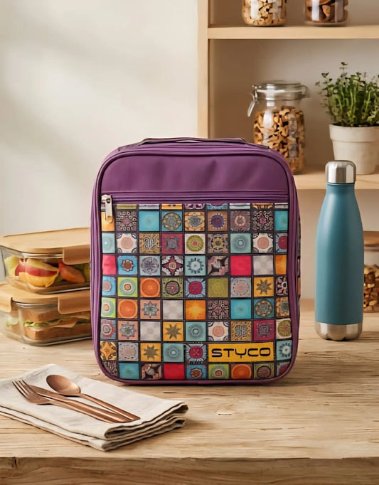 Colorful patterned lunch bag with 'Styco' branding on a wooden table with a water bottle and containers.