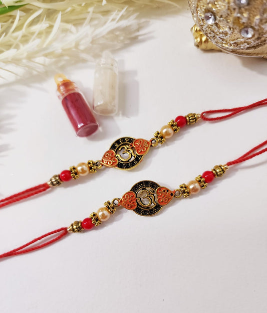 Two traditional Indian rakhi bracelets with red thread and decorative elements, displayed alongside a small bottle of tilak (a ceremonial mark).