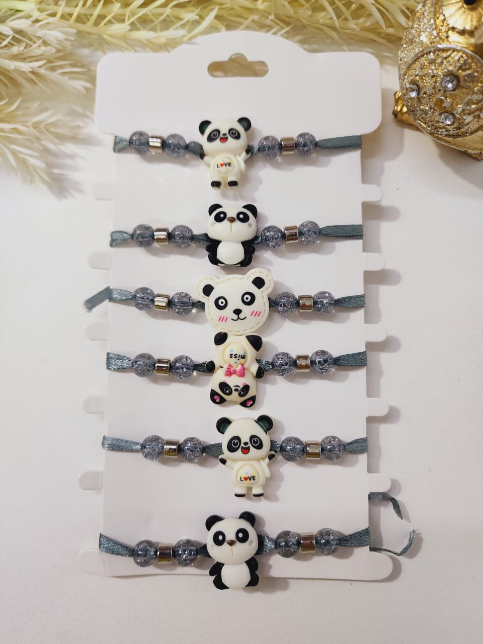 A collection of panda design rakhis with floral patterns and pearl beads on a white background.