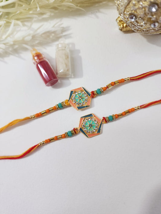 Two colorful designer rakhis with intricate patterns and embellishments placed on a white surface, accompanied by a small decorative item.