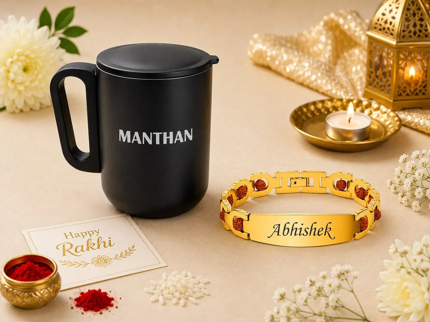 A personalized Rakhi gift set featuring a black insulated mug with the name 'MANTHAN' and a gold-plated bracelet with red stones and a central nameplate engraved 'Abhishek'. The set is styled with a 'Happy Rakhi' card, red powder, white flowers, and a gold lantern on a beige background.