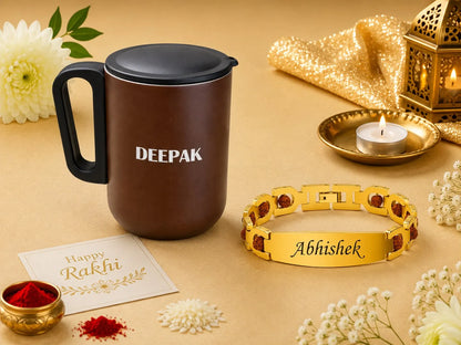 A styled product arrangement on a warm beige surface featuring a dark brown insulated mug with a black lid and handle, a gold engraved bracelet with red stones and the name 'Abhishek', a small card reading 'Happy Rakhi', red powder, flowers, a lit candle in a brass holder, and a gold lantern.