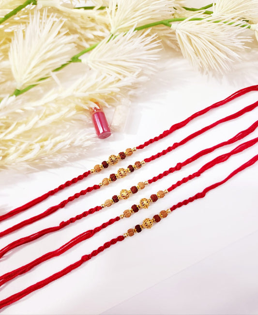 Three red strings with gold and brown beads on a white background with flowers.