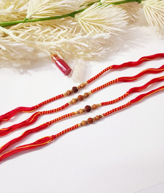 Red and gold beaded bracelets on a white background with dried plants.