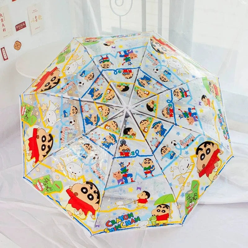 A clear plastic umbrella with a colorful cartoon print of Crèène characters, shown open on a white bed.