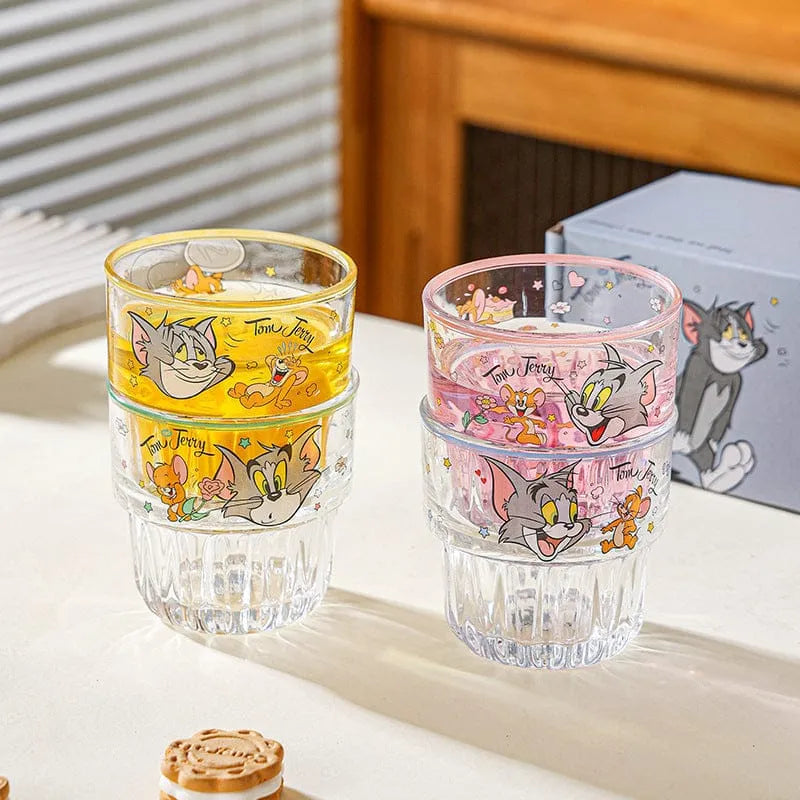 Two stackable glasses with cartoon character designs on a light surface.
