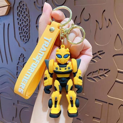 Yellow and black robot keychain with 'Transformers' branding held by a hand against a decorative background.