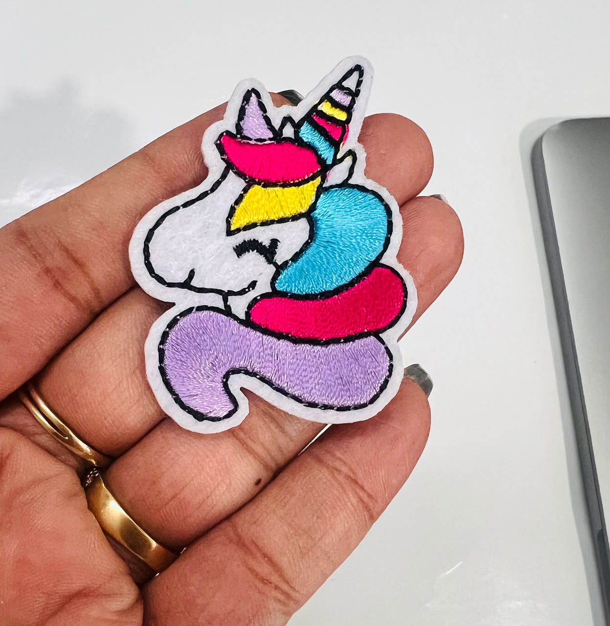 Colorful unicorn patch held in a hand with a white background