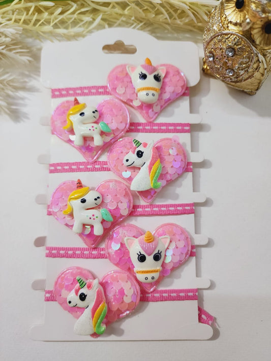 A collection of pink and white glittery rakhi bracelets with unicorn designs displayed on a card.