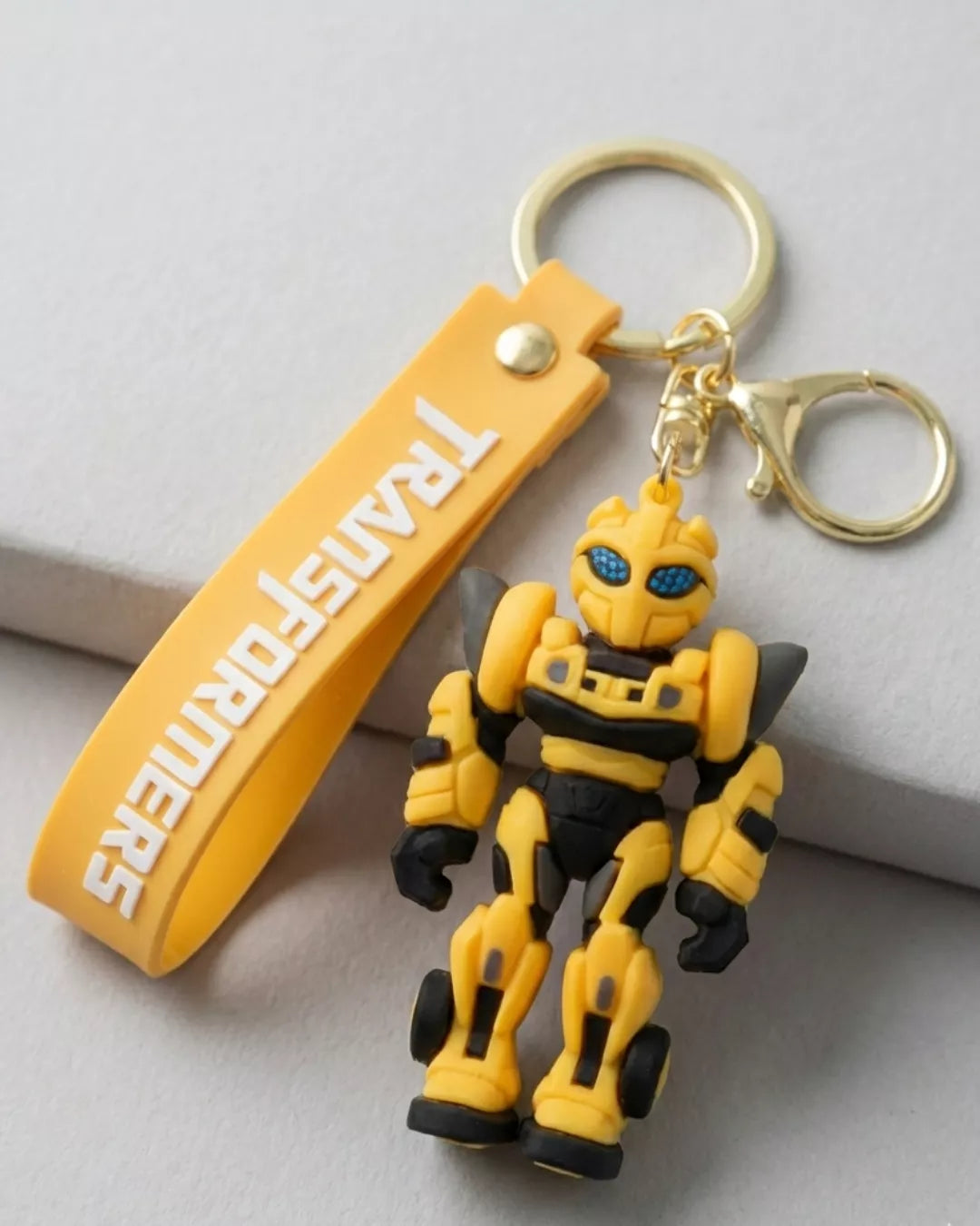 Yellow robot keychain with 'Transformers' branding on a light gray background