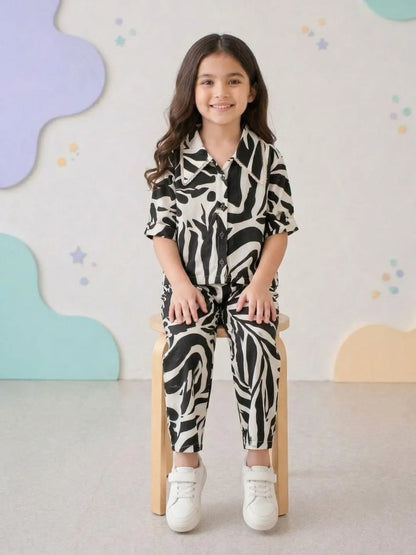 Child wearing a zebra print outfit sitting on a chair with a colorful wall background