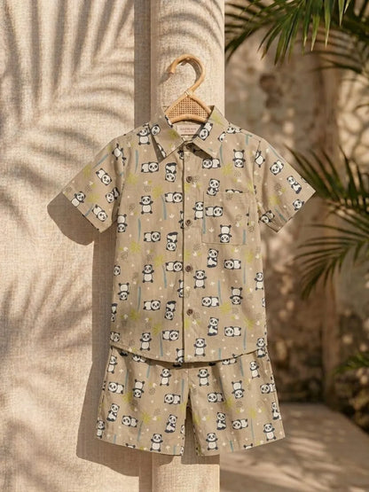 Children's shirt and shorts set with panda pattern on a hanger against a textured wall.