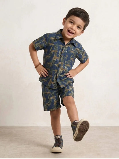 Child wearing a blue camouflage shirt and shorts set on a plain background