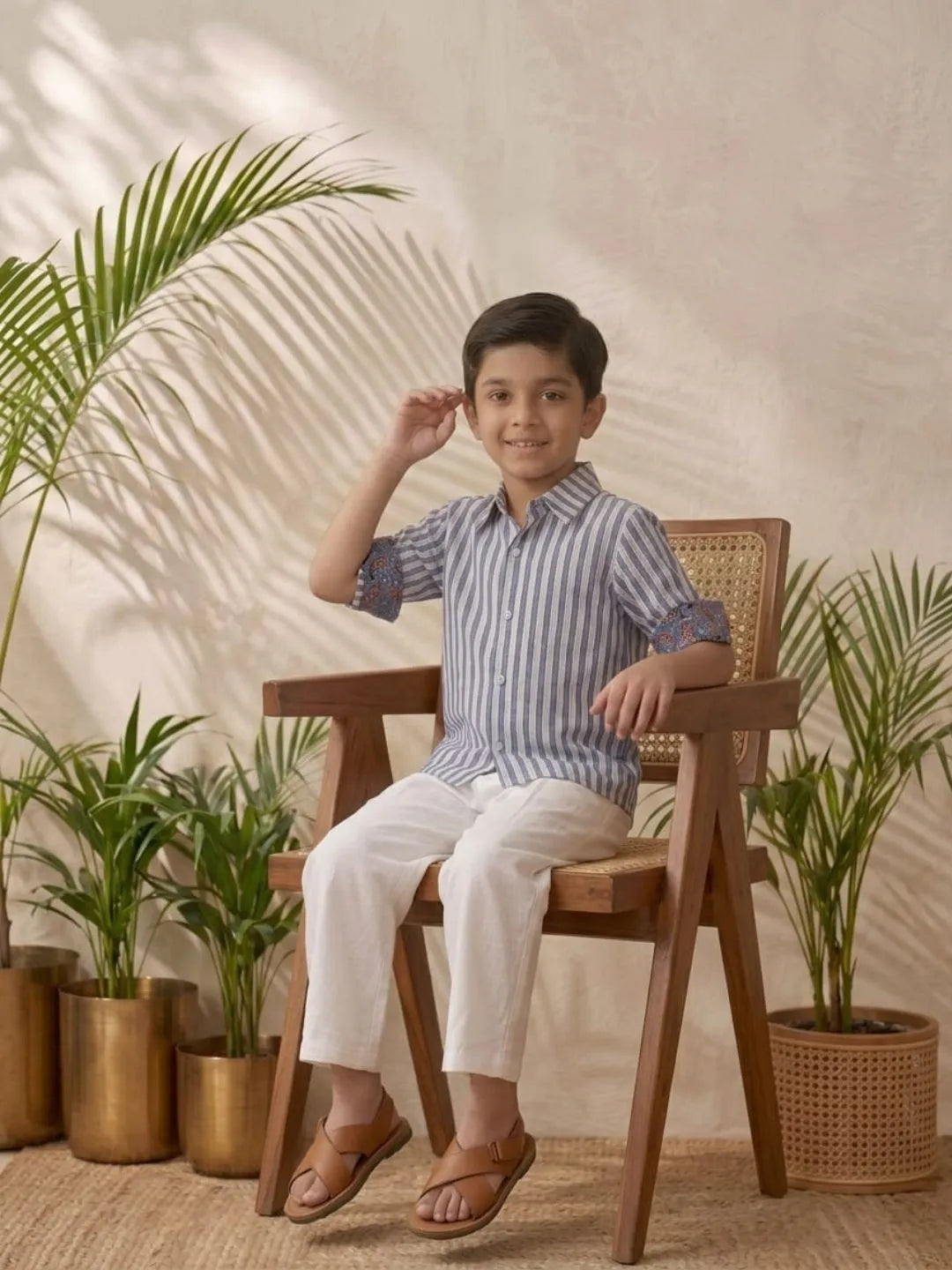 Boys blue striped cotton shirt with white trouser co-ord set sitting pose summer outfit