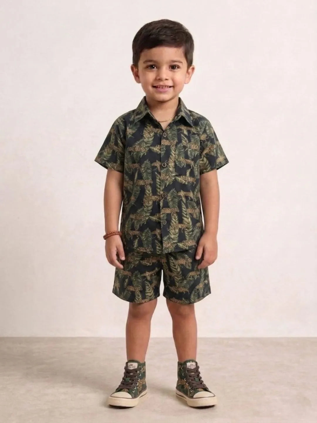 Child wearing a camouflage outfit with a shirt and shorts on a plain background