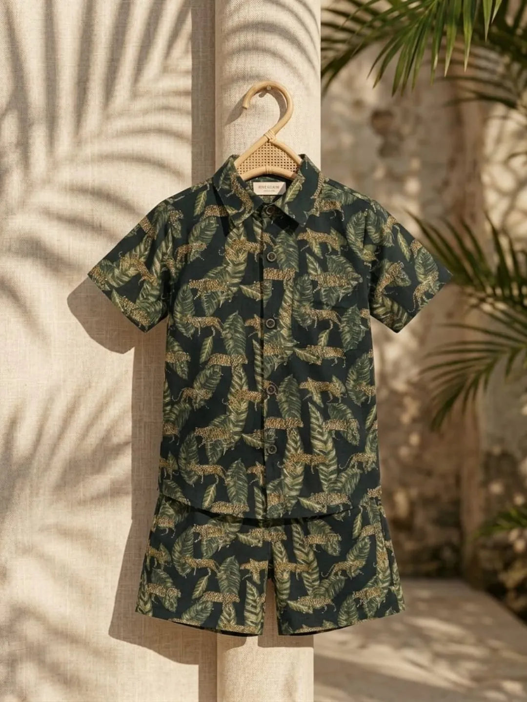 Green camouflage shirt and shorts set on a hanger with leafy background