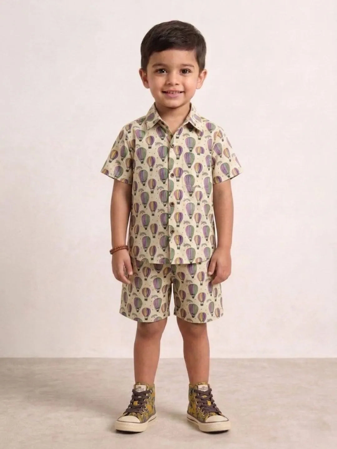 Child wearing a patterned shirt and shorts set on a plain background