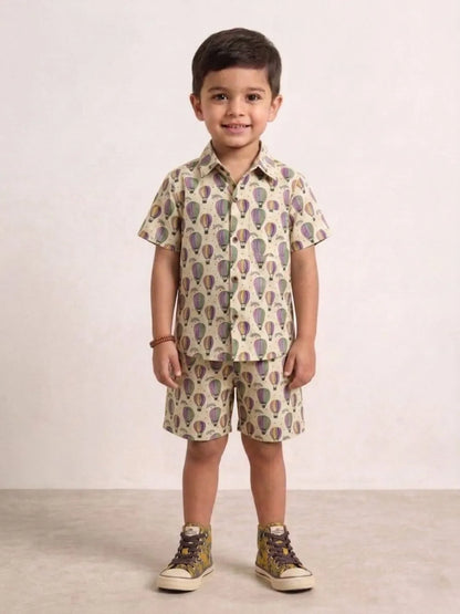 Child wearing a patterned shirt and shorts set on a plain background