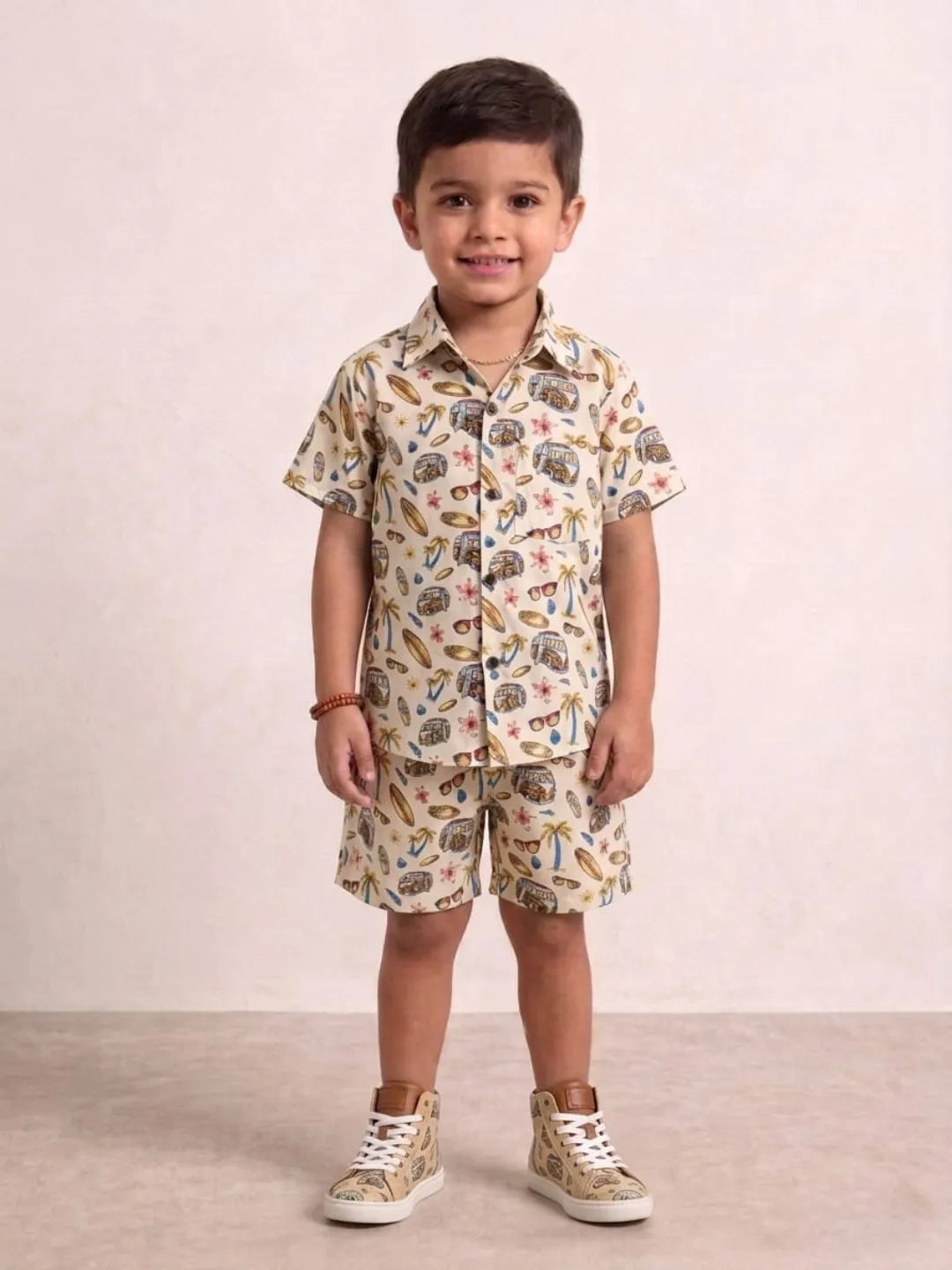 Child wearing a patterned shirt and shorts set with sneakers on a plain background