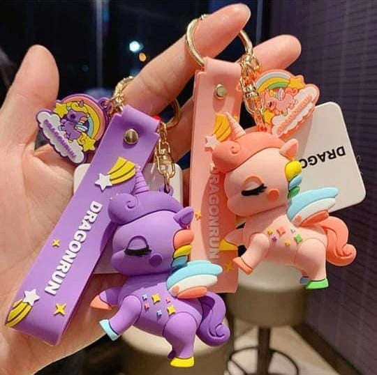 Two colorful dragon-shaped keychains held by a hand with a blurred background.