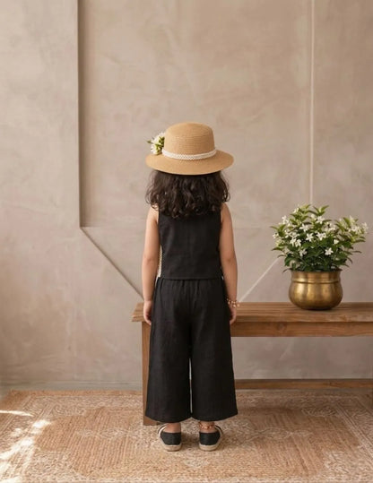 Lifestyle shot of little girl in black cotton co-ord set in a soft neutral background