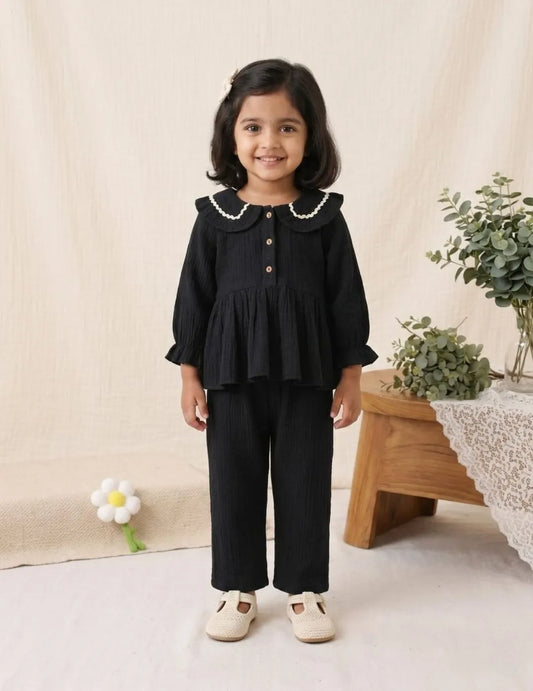 girl wearing black cotton co-ord set front view with scalloped collar top and pants