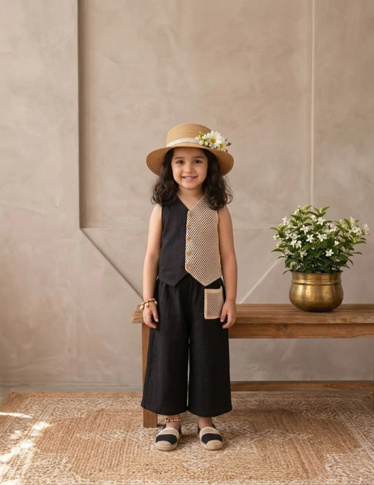 Front view of little girl wearing black cotton co-ord set with contrast panel and hat